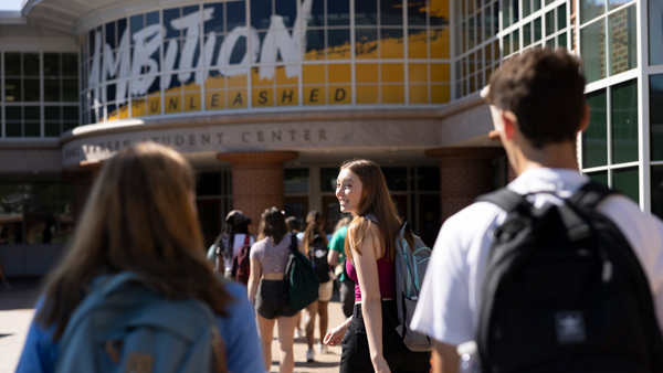 A transfer student looks over her shoulder and smiles as she walks into the student center during Orientation