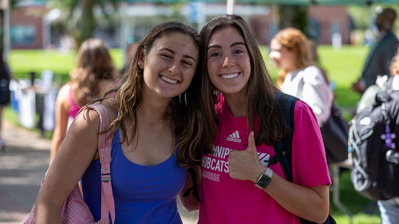 Two girls holding a thumbs up while smiling