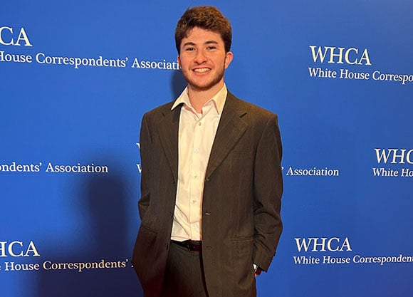 Jack Spiegel poses in front of a blue backdrop that reads 'White House Correspondent's Association'