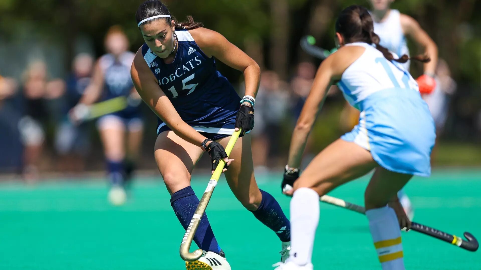 Quinnipiac field hockey player reaches for the ball during a game