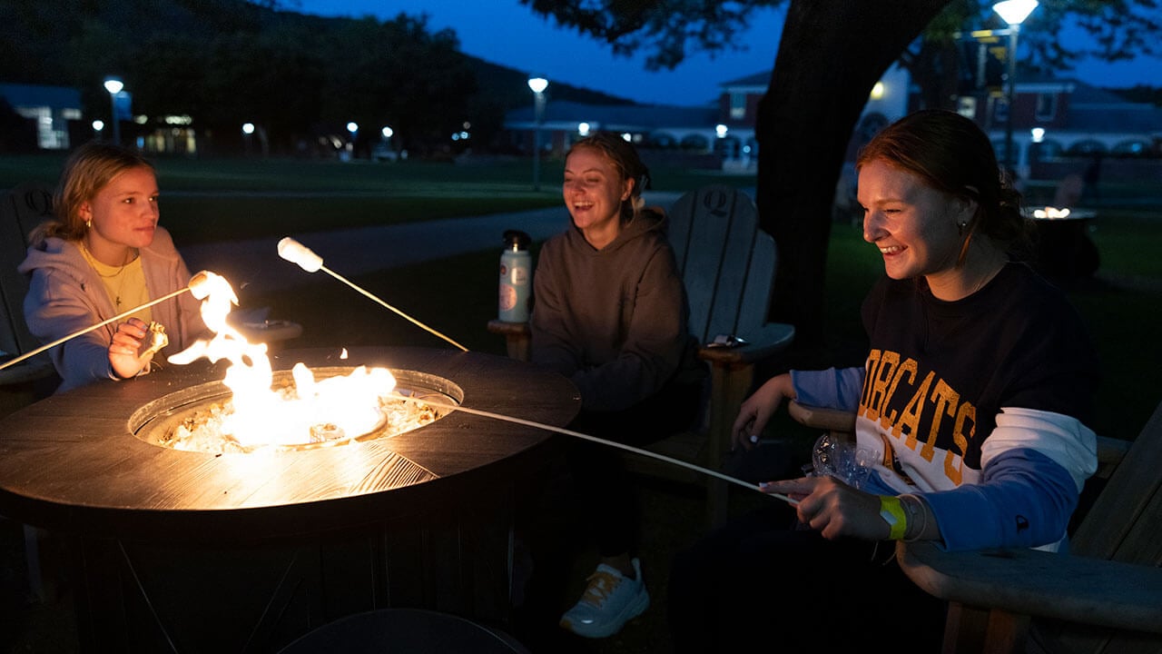 Friends toast marshmallows on the Quad