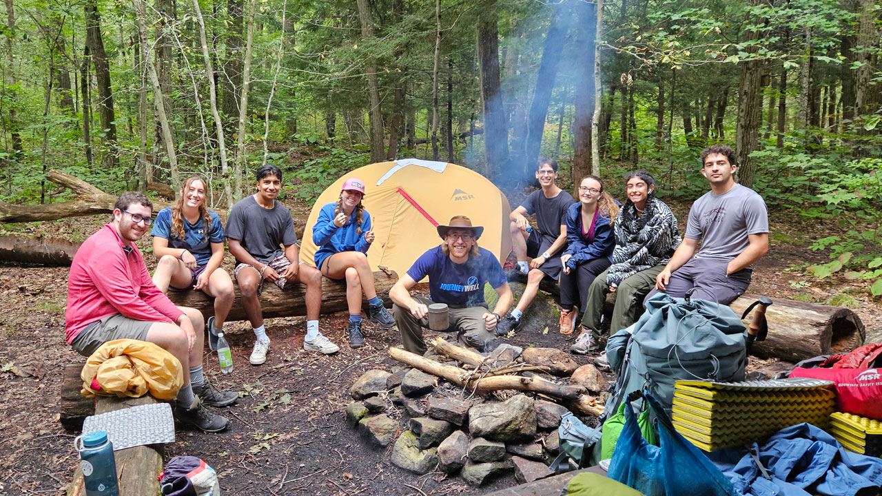 Students sit by a camp fire