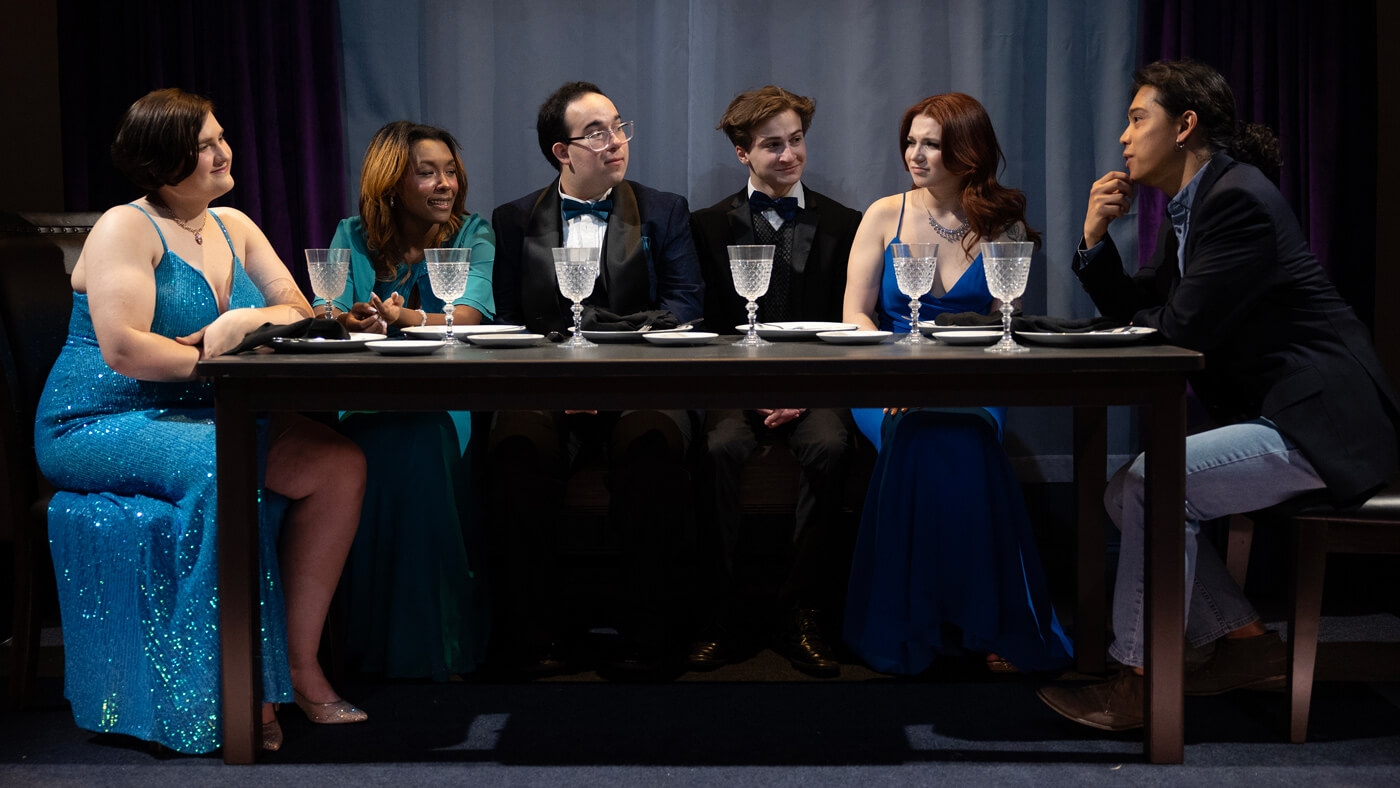 Quinnipiac actors and actresses seated at a formal dinner during the Friend Animals production.