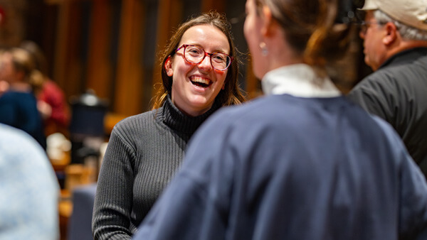 Two women, one in a judge's robe, smiling and having a conversation.