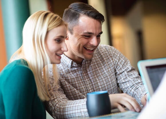 a male and a female student looking at a computer smiling