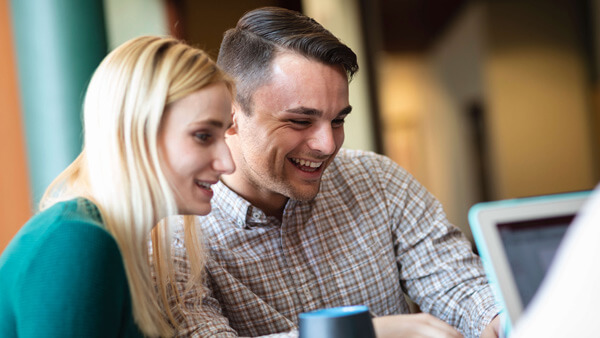 a male and a female student looking at a computer smiling