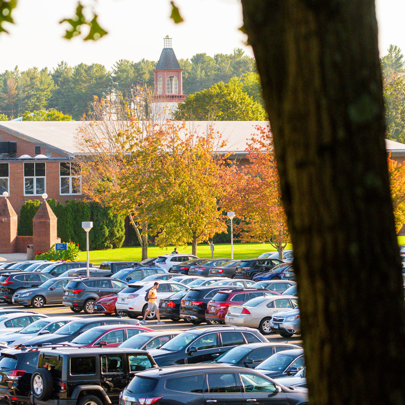 A student walks by parked cars on the Mount Carmel Campus.