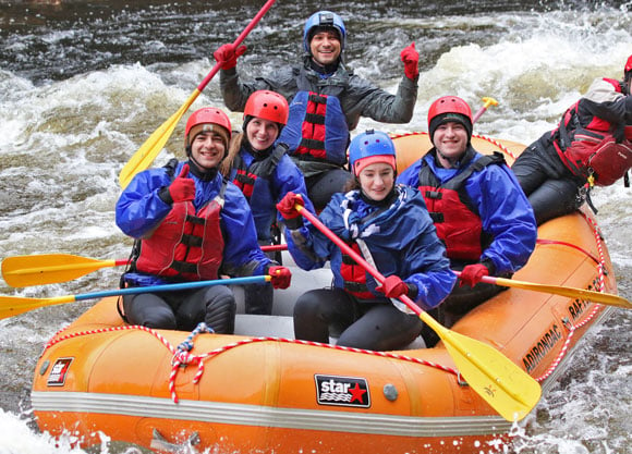 A group of students is pictured white water rafting in a river.