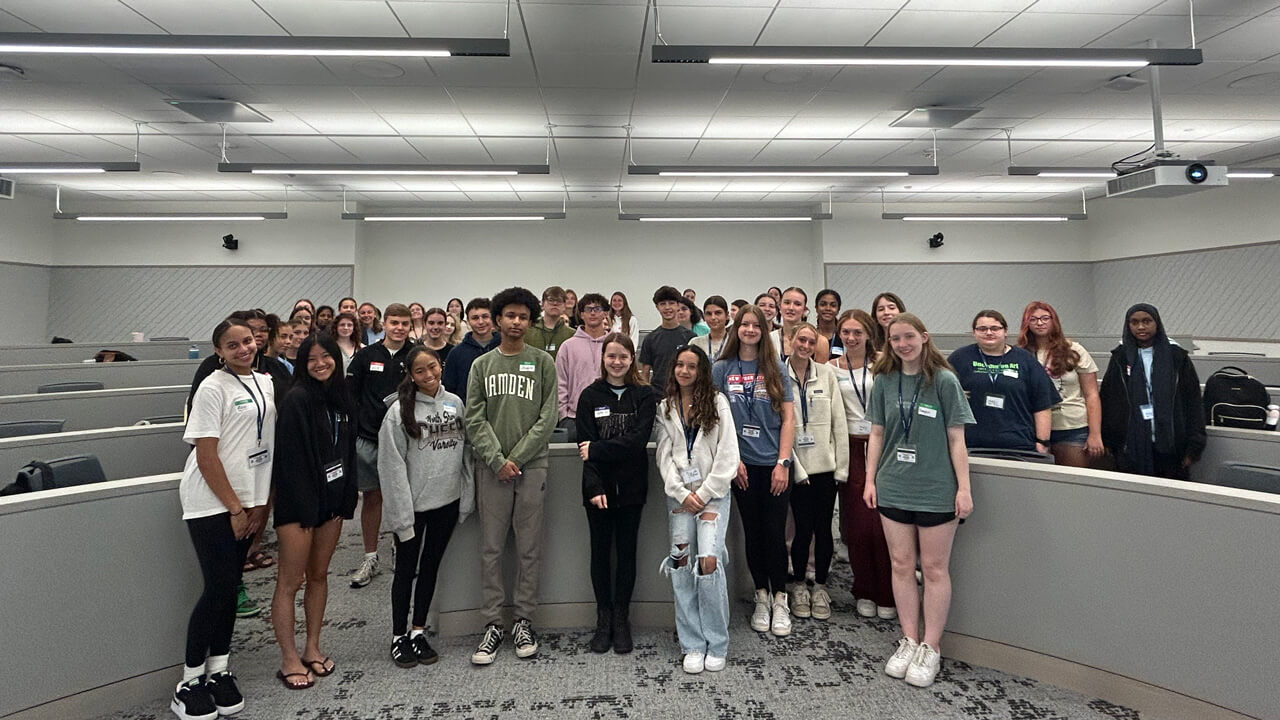 A large group shot of all of the student participants standing in the front of a classroom.