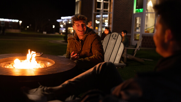 Students sit in front of the firepit