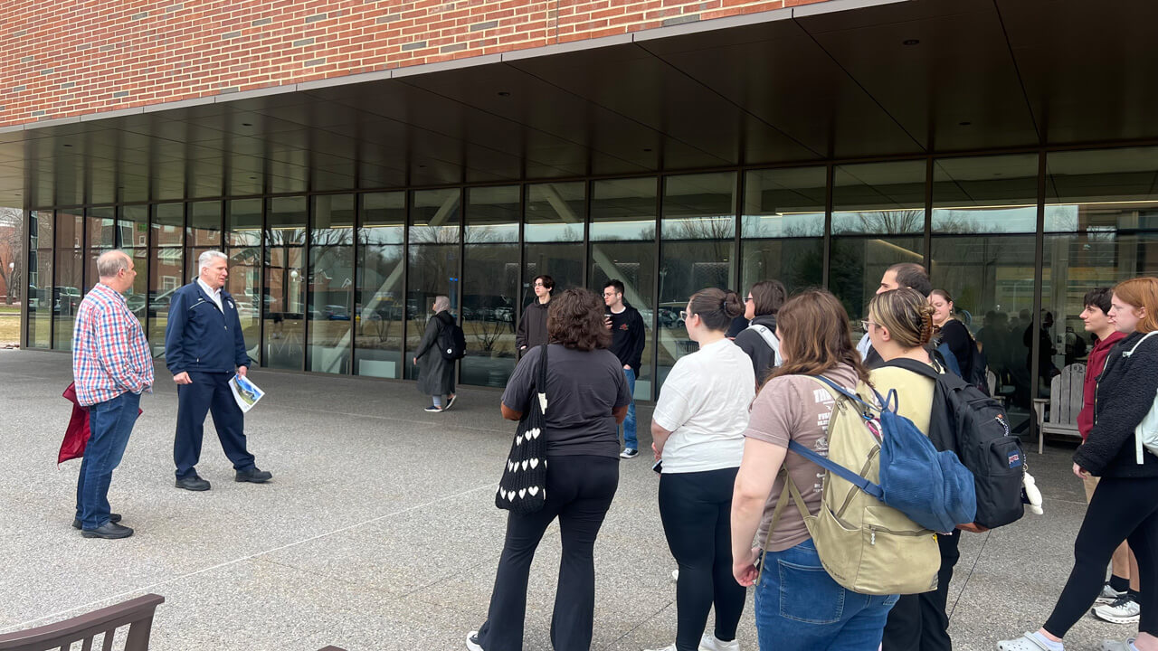 The students, professor and Facilities member standing outside the glass windows of The SITE before their tour.