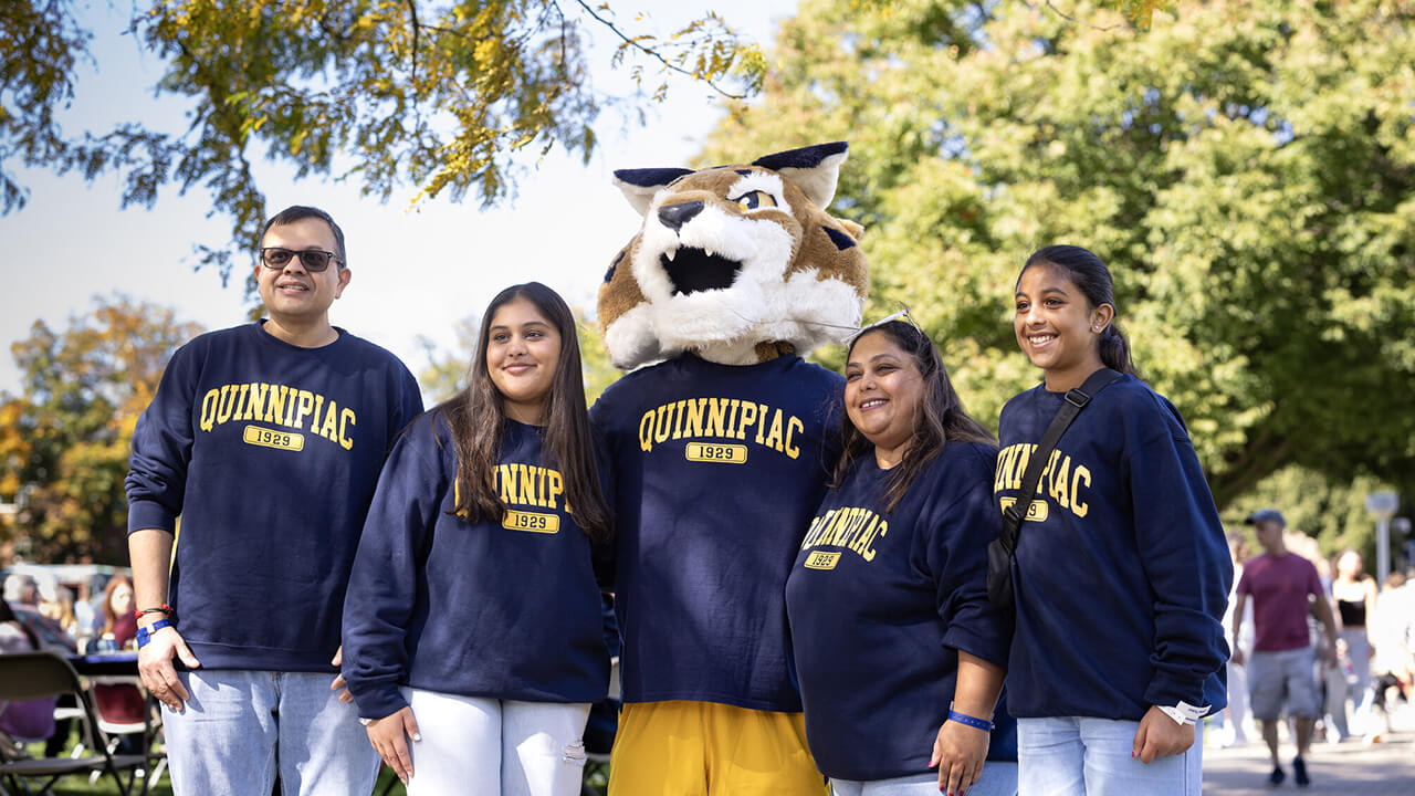 Family wearing matching Quinnipiac shirts with Boomer.