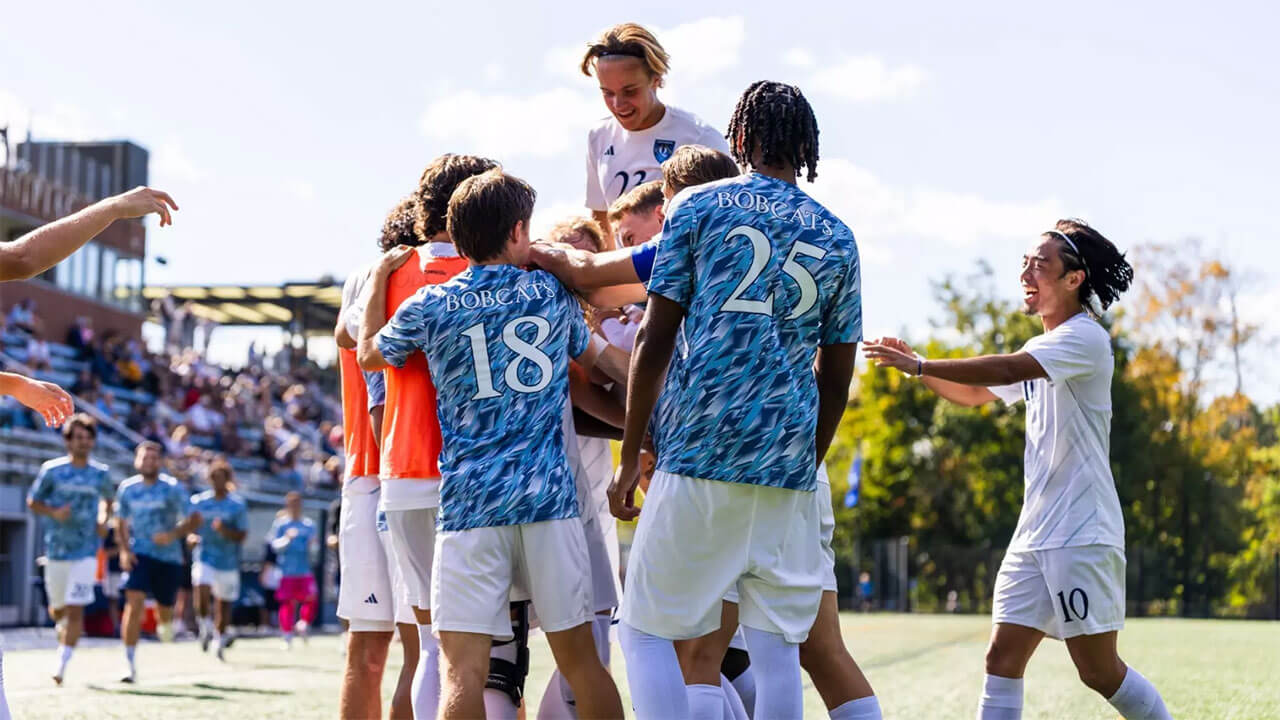 Soccer players embrace in celebration on the field.