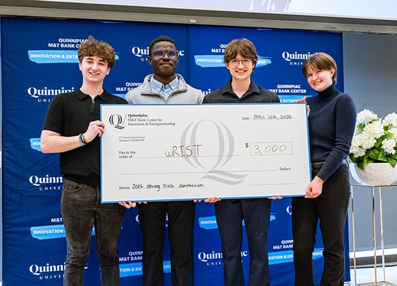 Four students hold a $3,000 prize check at a Quinnipiac entrepreneurship competition.