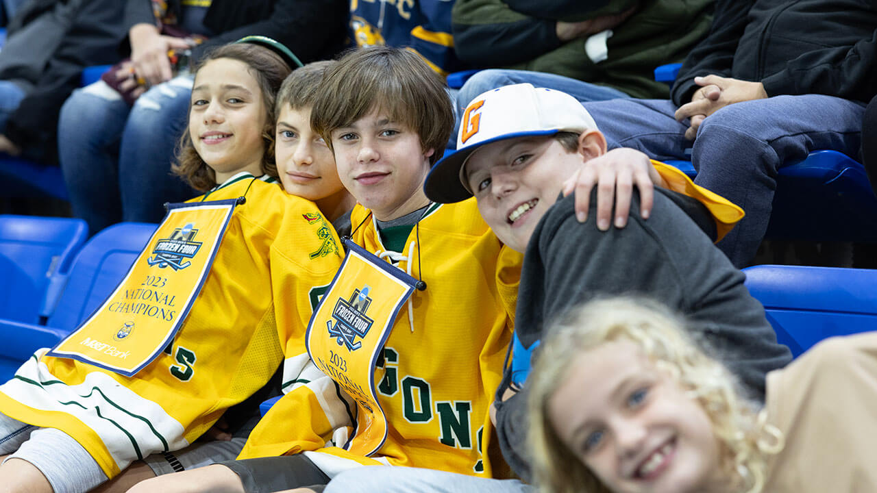 Three children smile for a photo wearing Quinnipiac gear