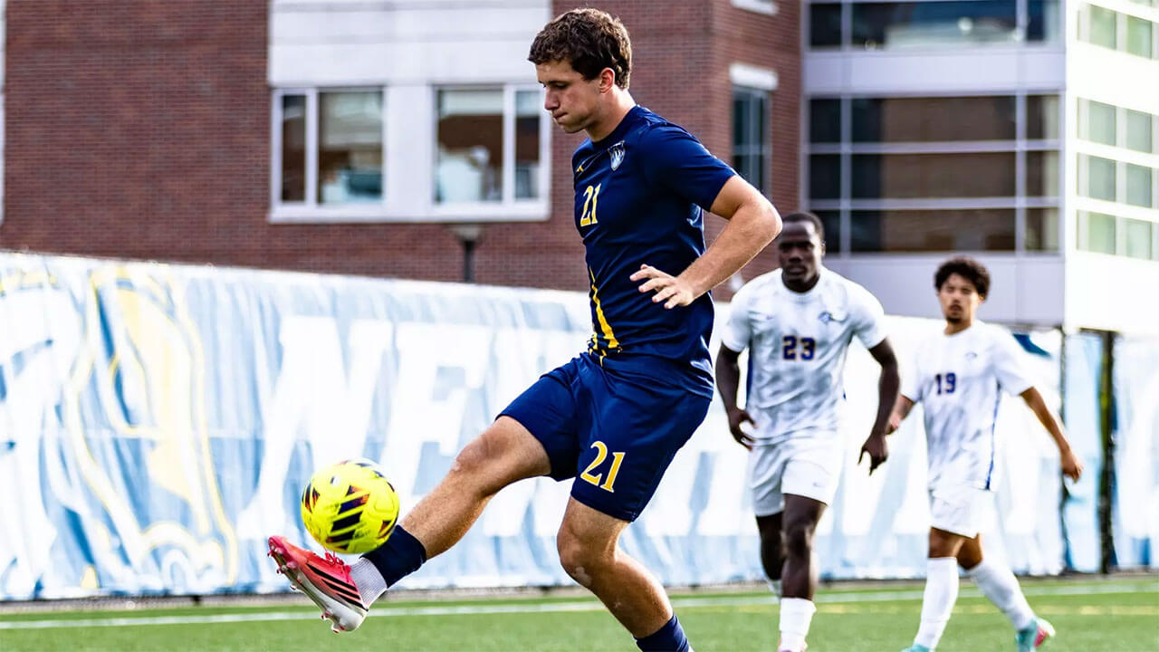 Member of the men's soccer team kicks the ball.