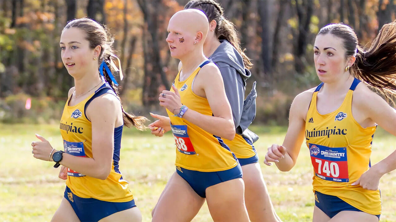 Members of the women's cross country team run in yellow Quinnipiac tank tops.