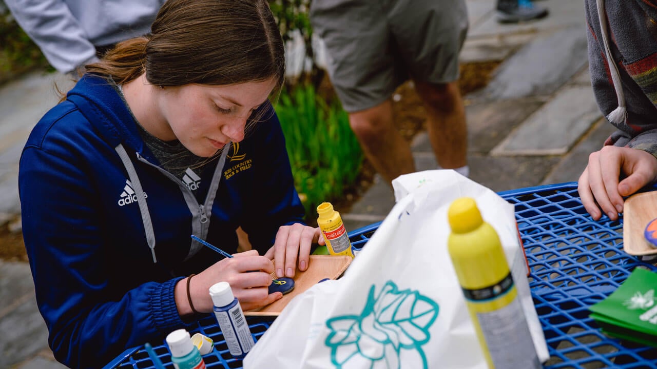 Student paints a Quinnipiac "Q'" on a rock