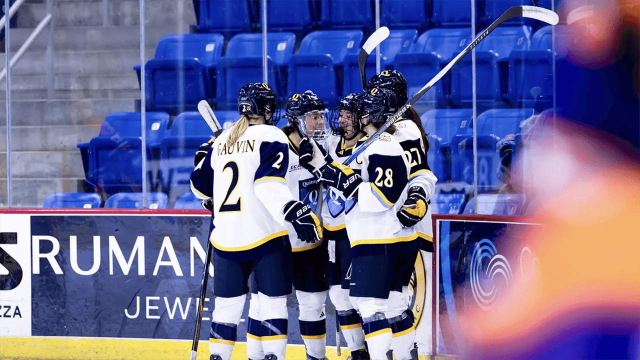 Women's ice hockey players celebrate after scoring a goal.