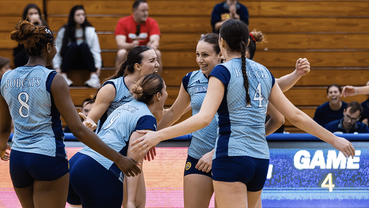 Women's volleyball players celebrate scoring point.