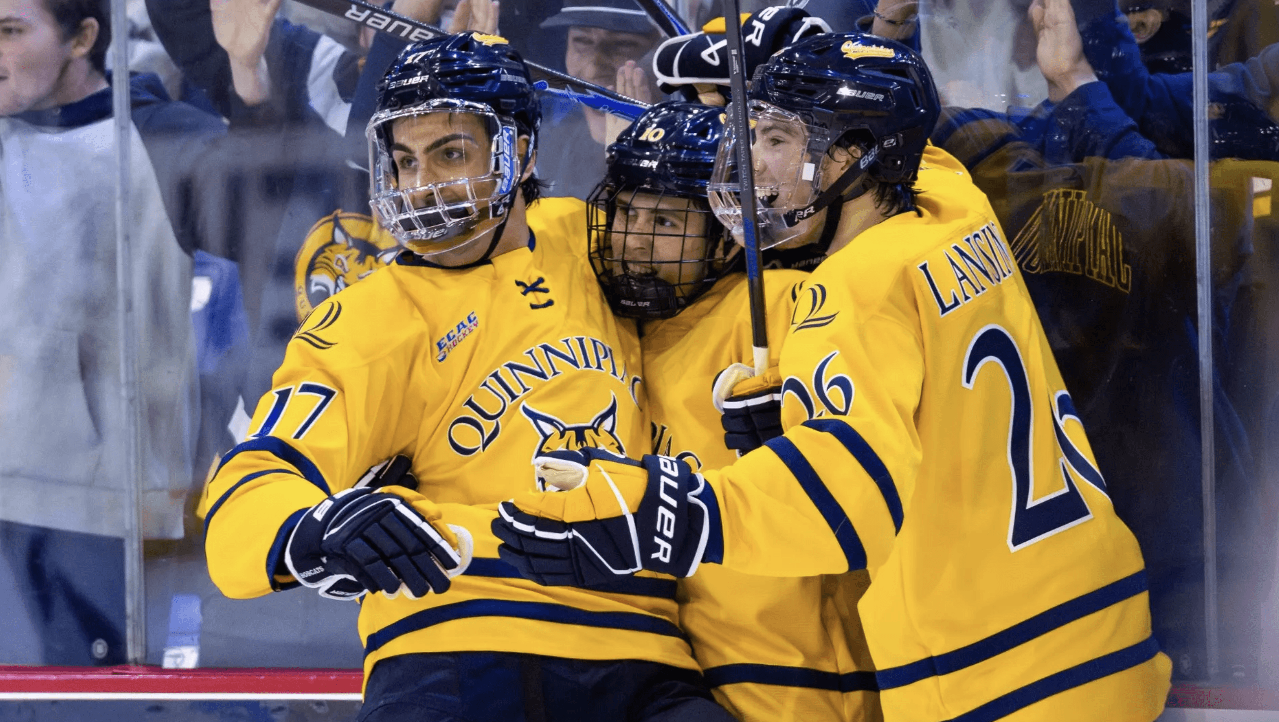 Men's ice hockey players embrace after scoring goal.