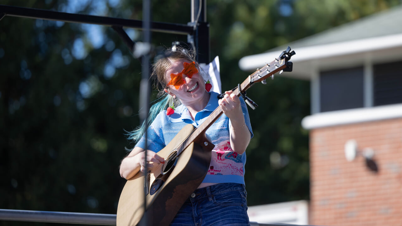 Person smiles and plays guitar