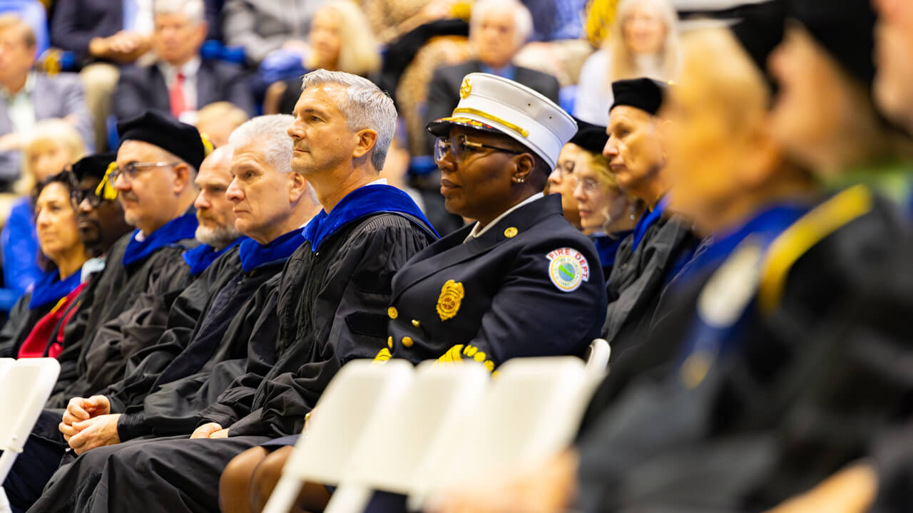 Audience members sit and look toward the stage