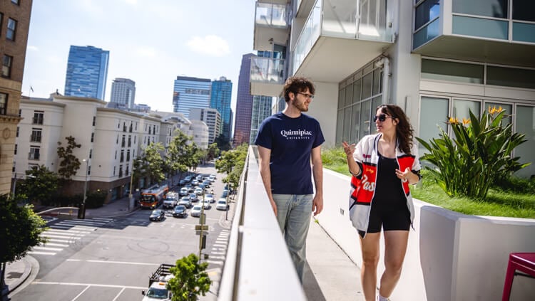 2 students walking outside on a balcony walkway