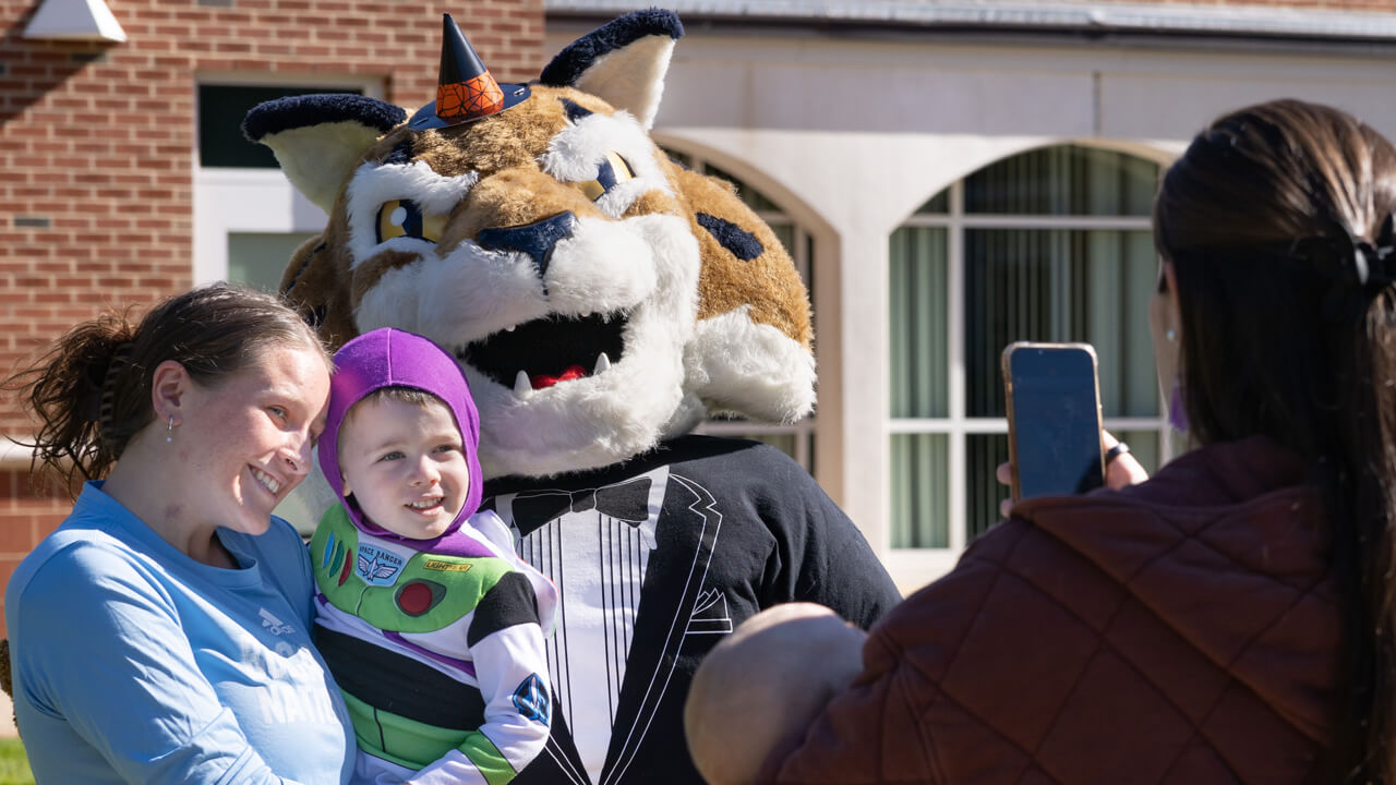 Boomer the mascot poses with two people