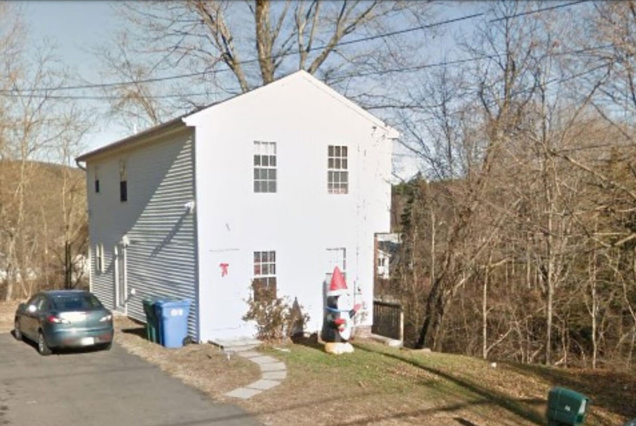 A two-story house with a car sitting in the driveway surrounded by nature on 48 Woodruff Street