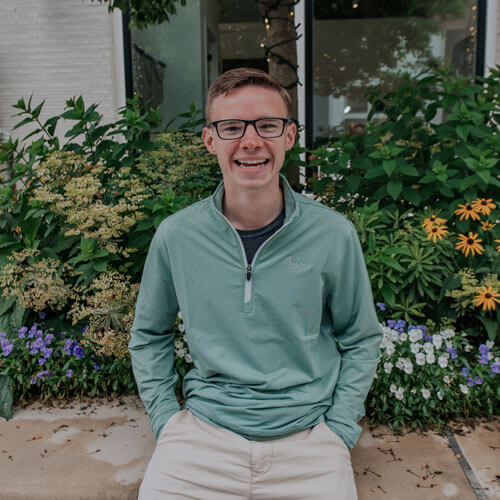 John Shepherd sits in front of flowers