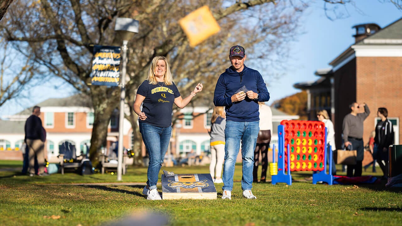 Two people play cornhole.