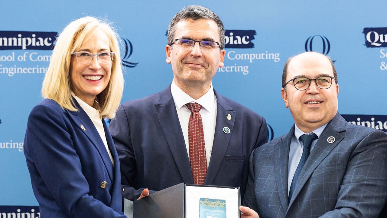 President Marie Hardin stands with two men recieving award for a photo.