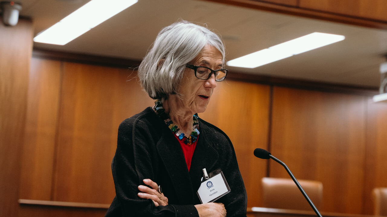 Speaker crossing her arms while talking into a microphone