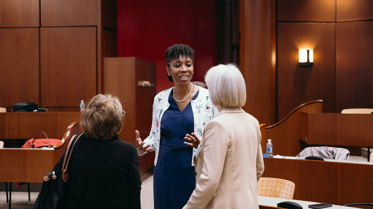 Three women standing in the auditorium talking to one another