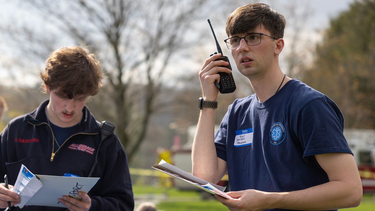 QU EMS member listening to a handheld radio during a Mass Casualty Drill