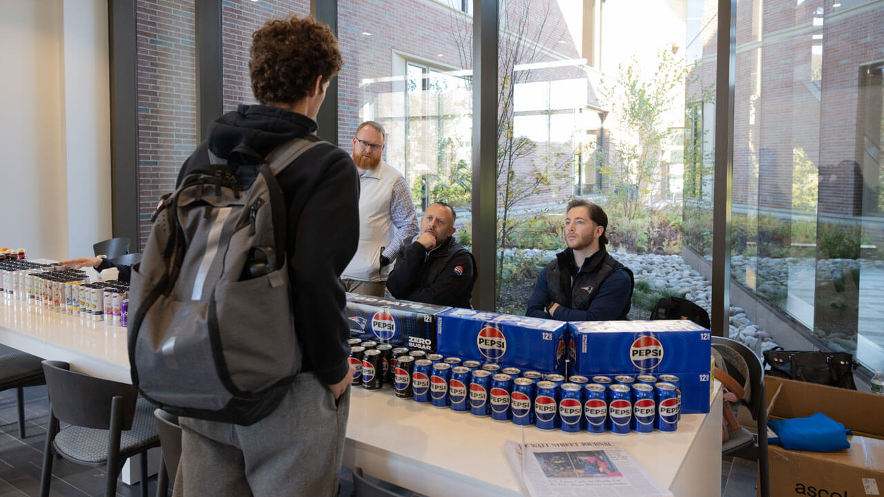 Student stands a pepsi table