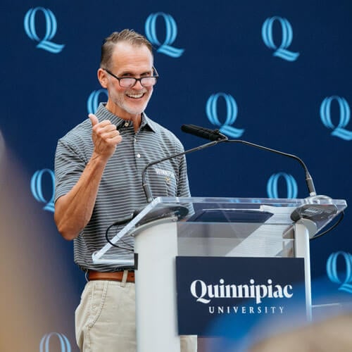 Photo of Thomas Ellett at a Quinnipiac podium.