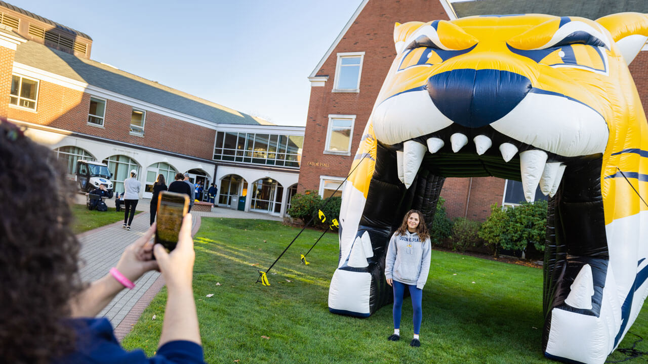 A family takes a photo under the inflatable boomer at the bobcat welcome celebration.