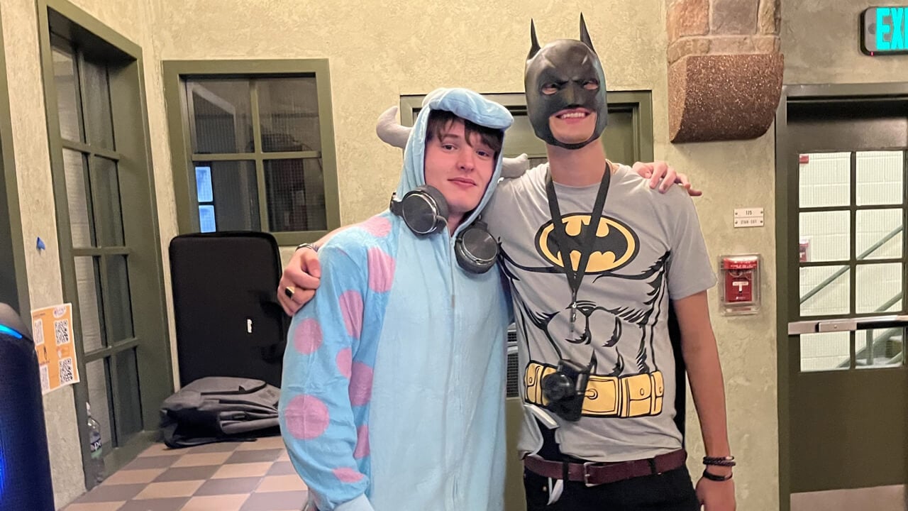 Two students dressed in costumes behind a DJ booth