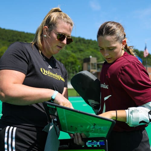 Photo of the Head Women's Field Hockey Coach, Nina Klein, talking to an athlete.