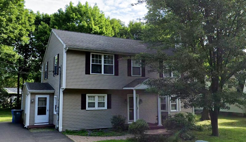 Grey, two-story house with red shutters and tree out front