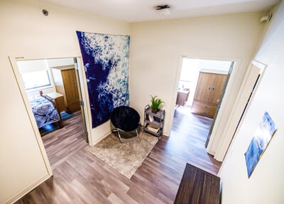 Interior view of apartment bedrooms with wood floors and colorful wall hanging