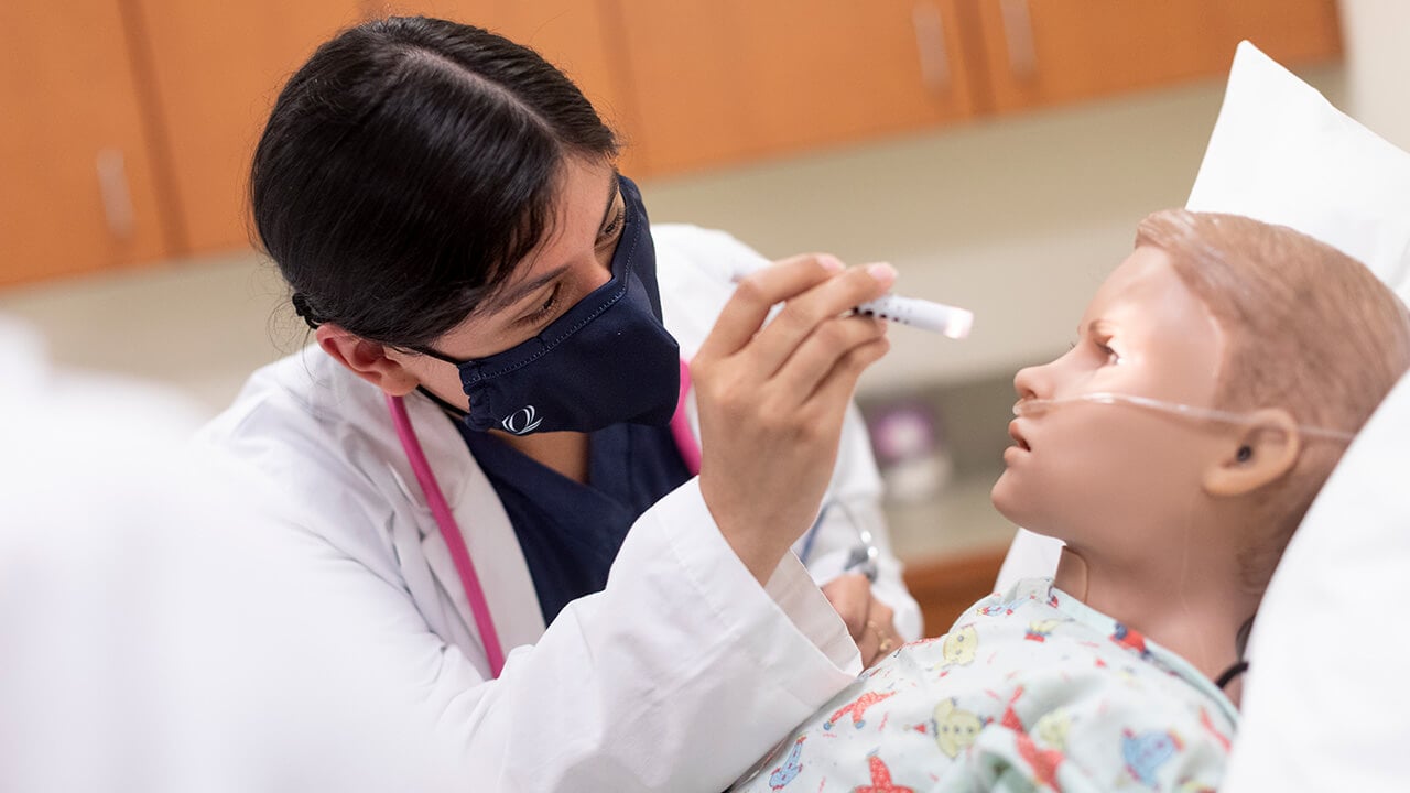 Nursing student Yessica Perez performs a health assessment on a pediatric high-fidelity mannequin.