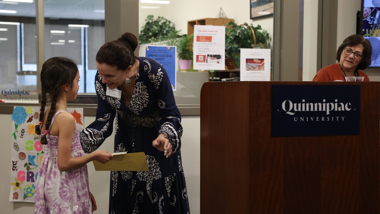 Education Dean Anne Dichele handing an award to a young girl