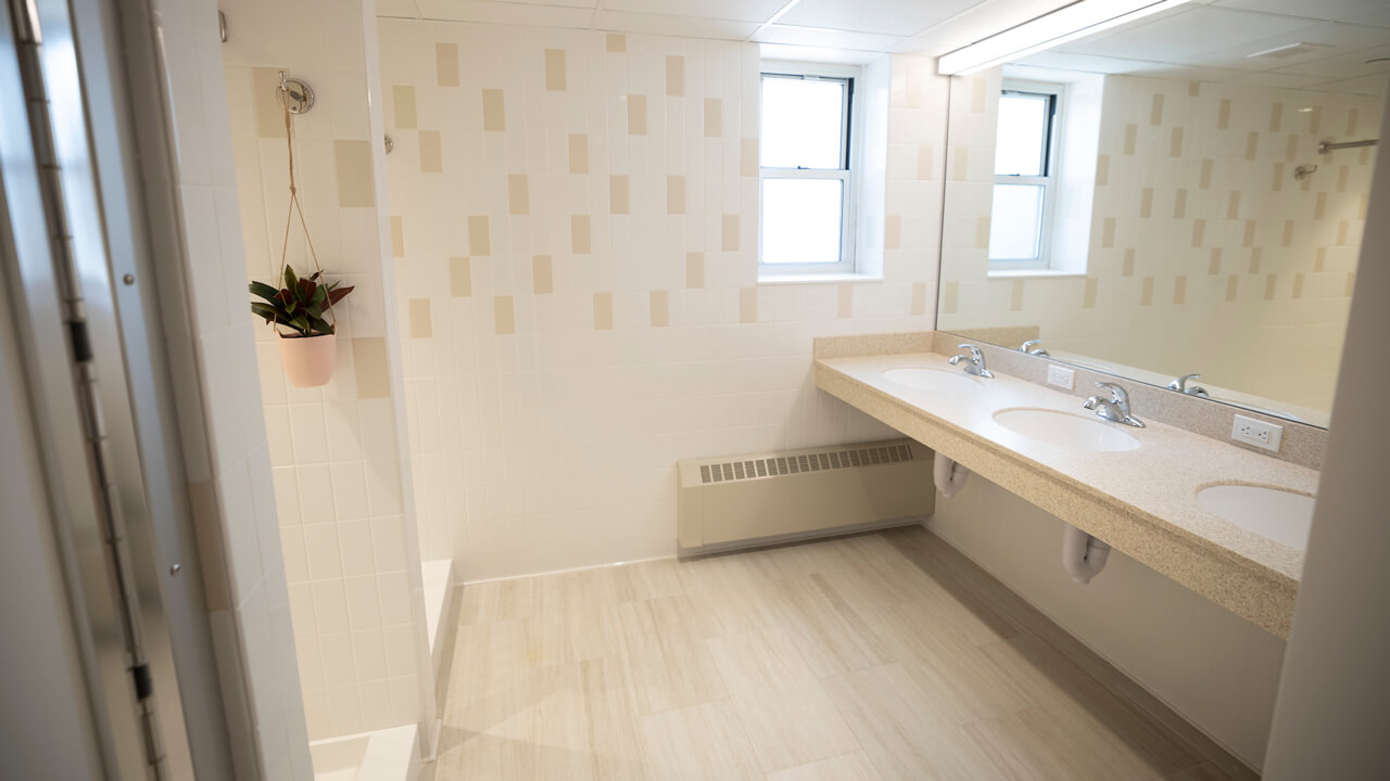 A shower and two sinks are shown in a common bathroom