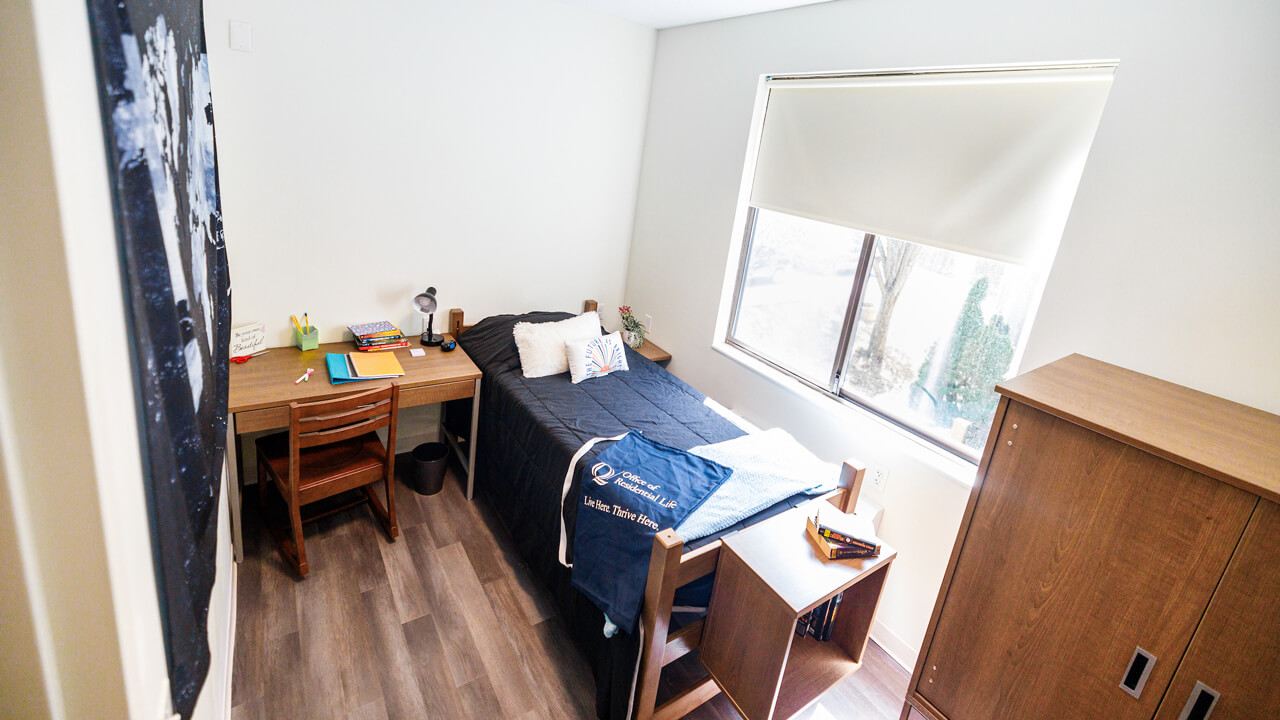 A desk and bed by a window next to a wardrobe