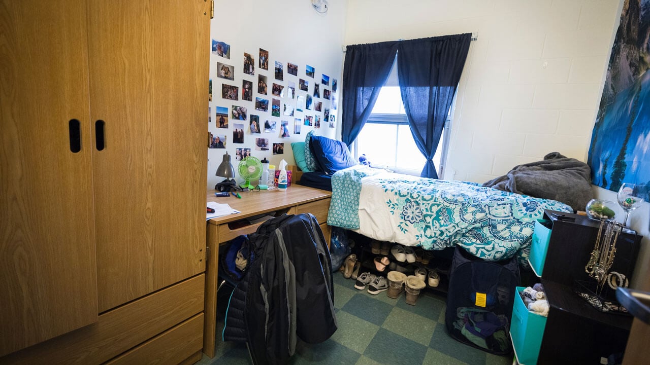 A single bedroom with a wardrobe, desk, chair, and personal window