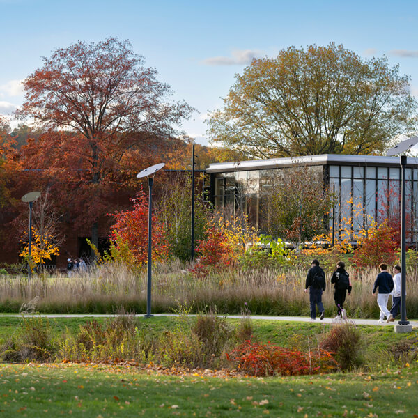 A group of students walk past the RecWell center on a blue sky fall day