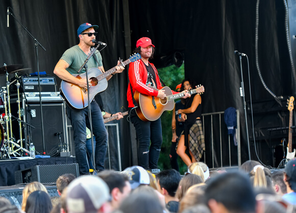 Plain White T's band members play on an outdoor stage with Quinnipiac students in the crowd